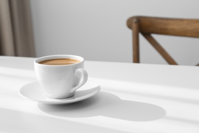 Photo of Cup of hot aromatic coffee on white table indoors. Space for text