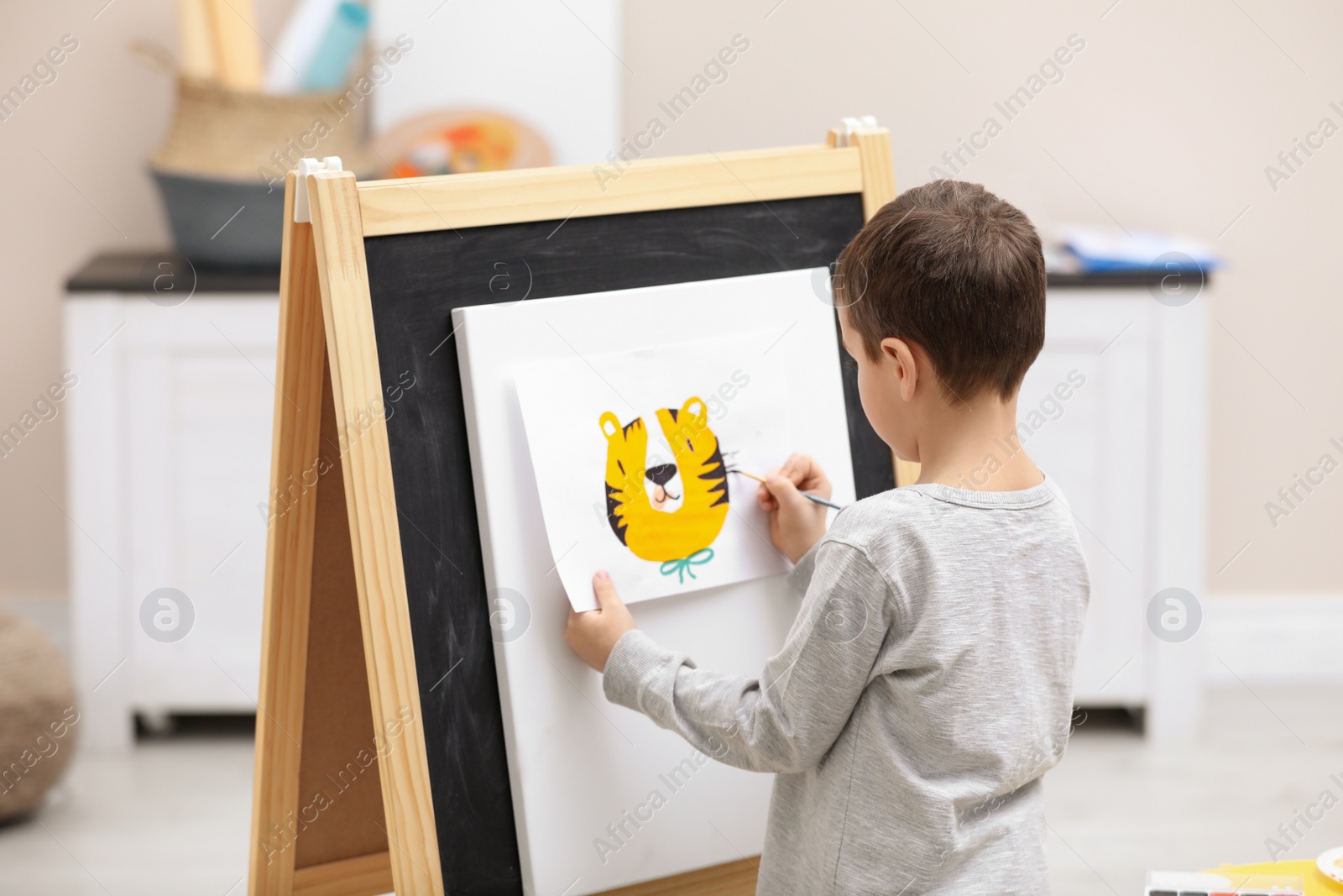Photo of Little child painting on easel in room