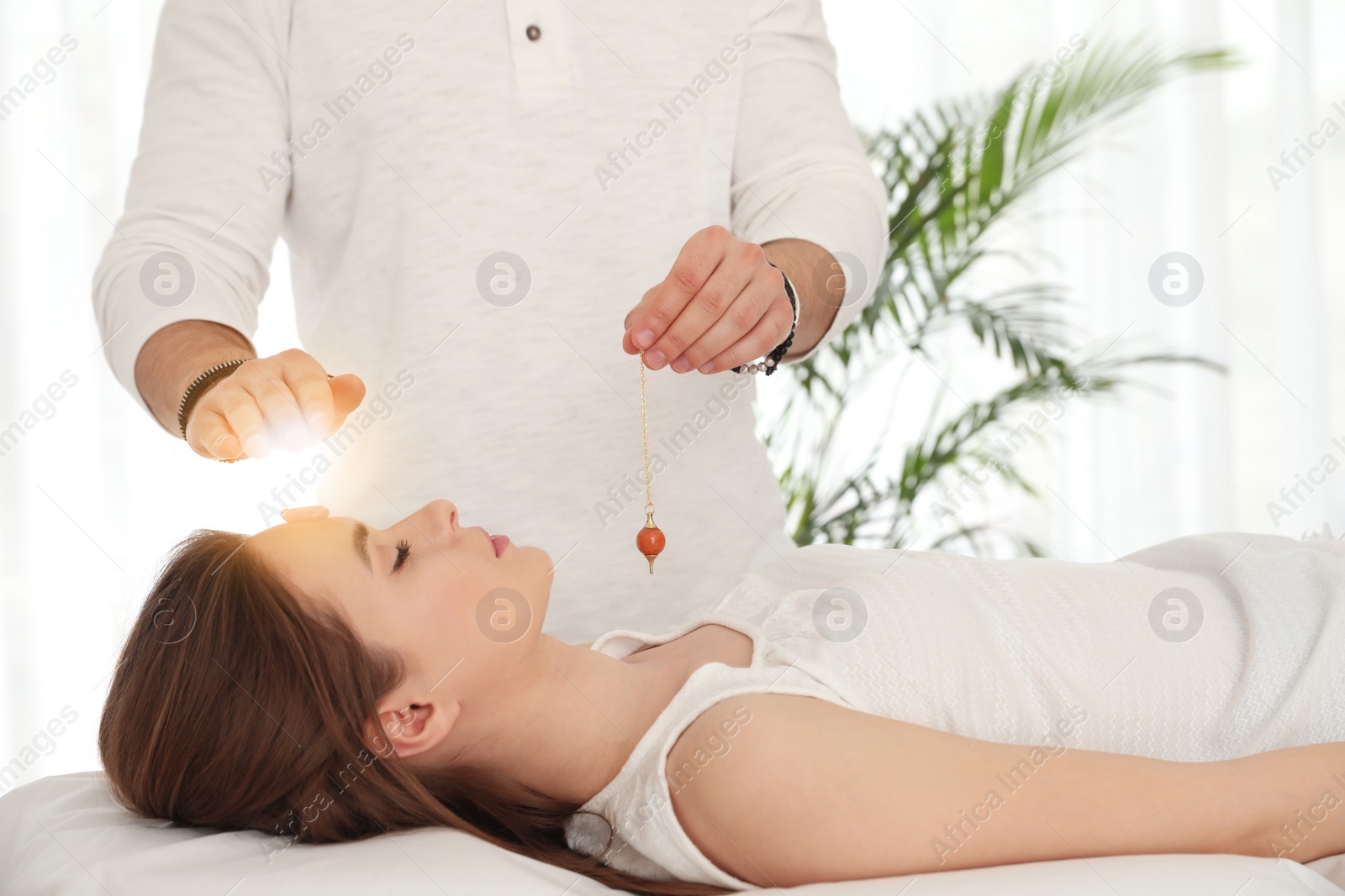 Photo of Young woman during crystal healing session in therapy room