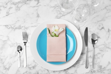 Beautiful table setting with cutlery, napkin, glasses and plates on marble background, top view
