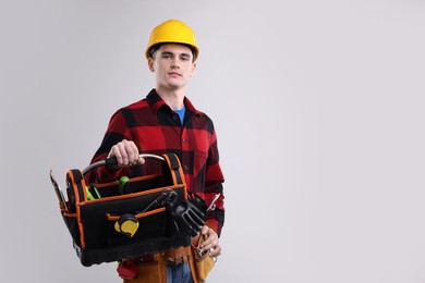 Photo of Professional repairman with tool box on light grey background. Space for text