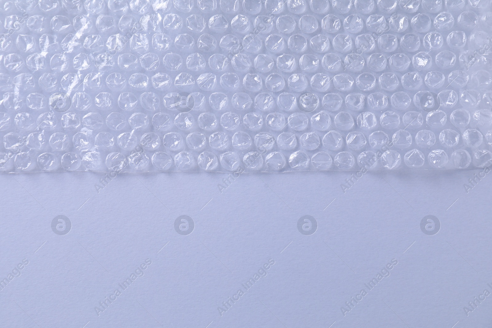 Photo of Transparent bubble wrap on gray background, top view. Space for text