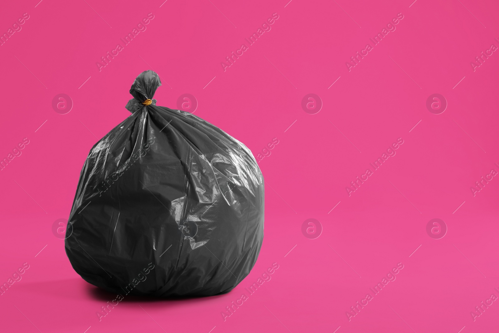 Photo of Trash bag full of garbage on pink background. Space for text