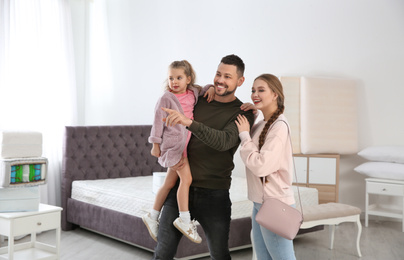 Happy family looking for mattress in furniture store