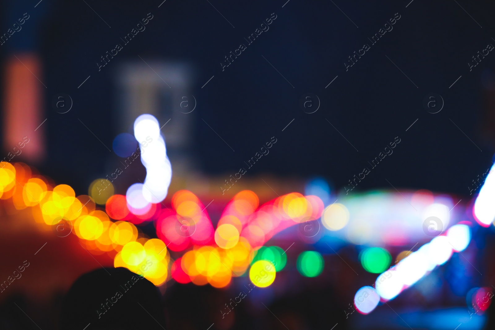 Photo of Blurred view of city street with festive lights at night. Bokeh effect