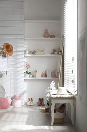 Shelves with different decorative elements, shoes and  bench in dressing room. Interior design