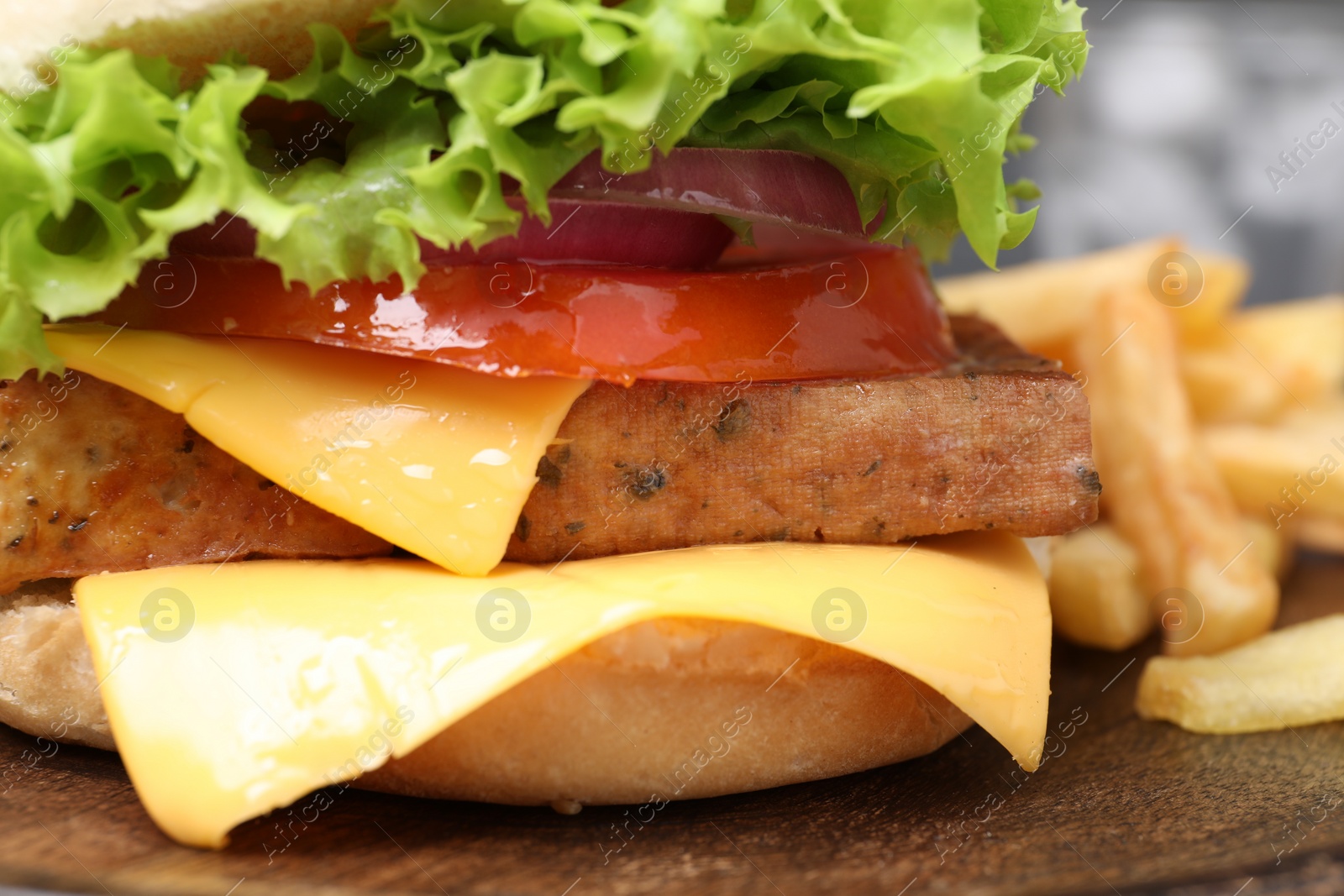 Photo of Delicious burger with tofu and fresh vegetables on wooden table, closeup