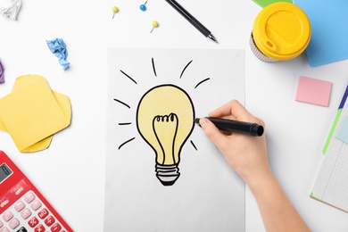 Photo of Woman drawing light bulb on white background. Business trainer concept