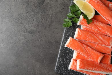 Photo of Fresh crab sticks with lemon on grey table, top view. Space for text