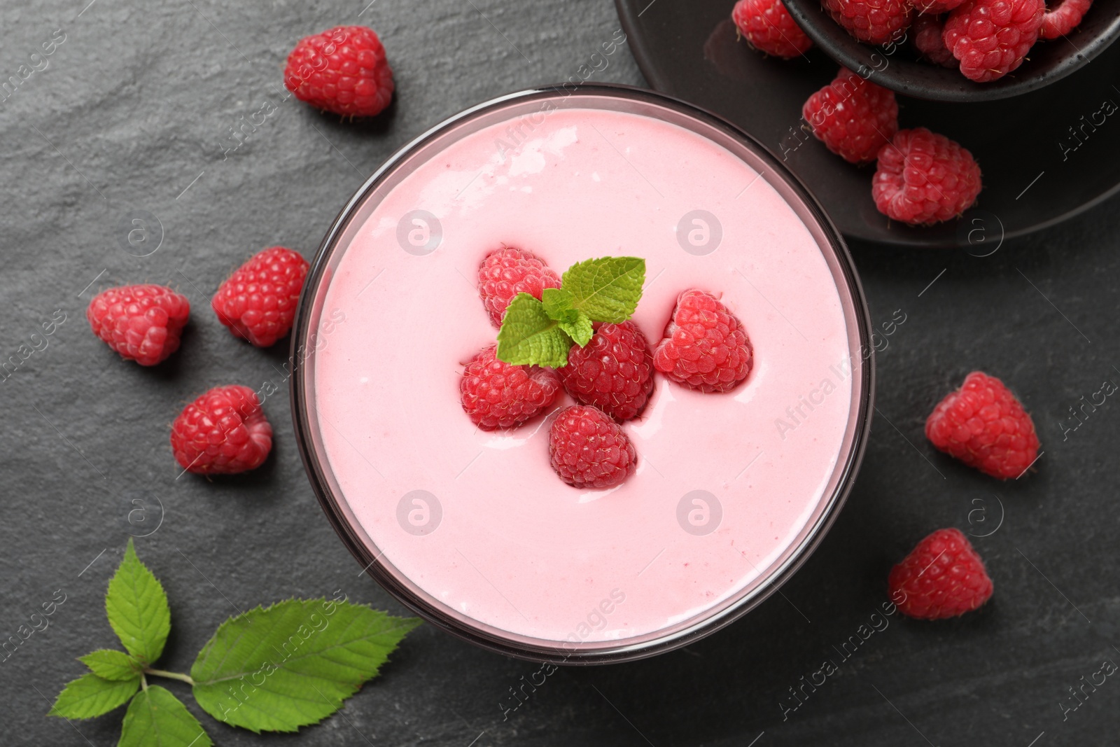 Photo of Delicious raspberry mousse with mint on black table, flat lay