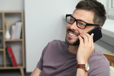 Happy man talking on smartphone at home