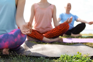 Photo of Group of women practicing yoga outdoors on sunny day