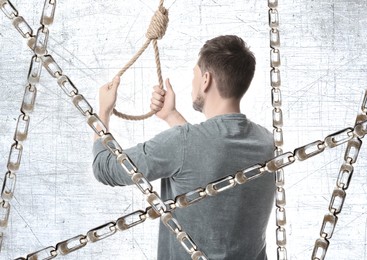 Man with rope noose and metal chains, back view