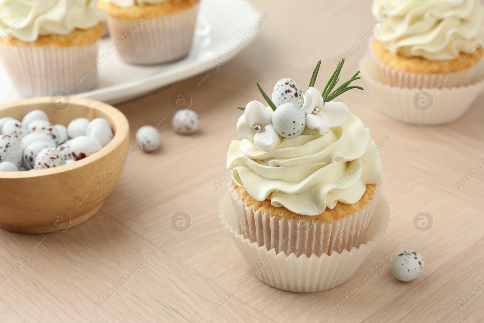 Photo of Tasty Easter cupcakes with vanilla cream on wooden table, closeup