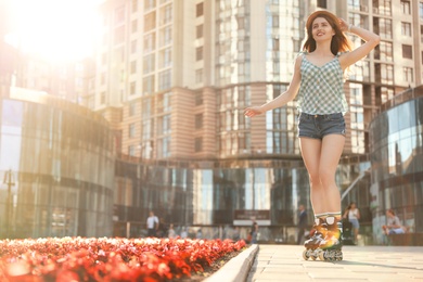 Photo of Beautiful young woman with roller skates having fun outdoors, space for text