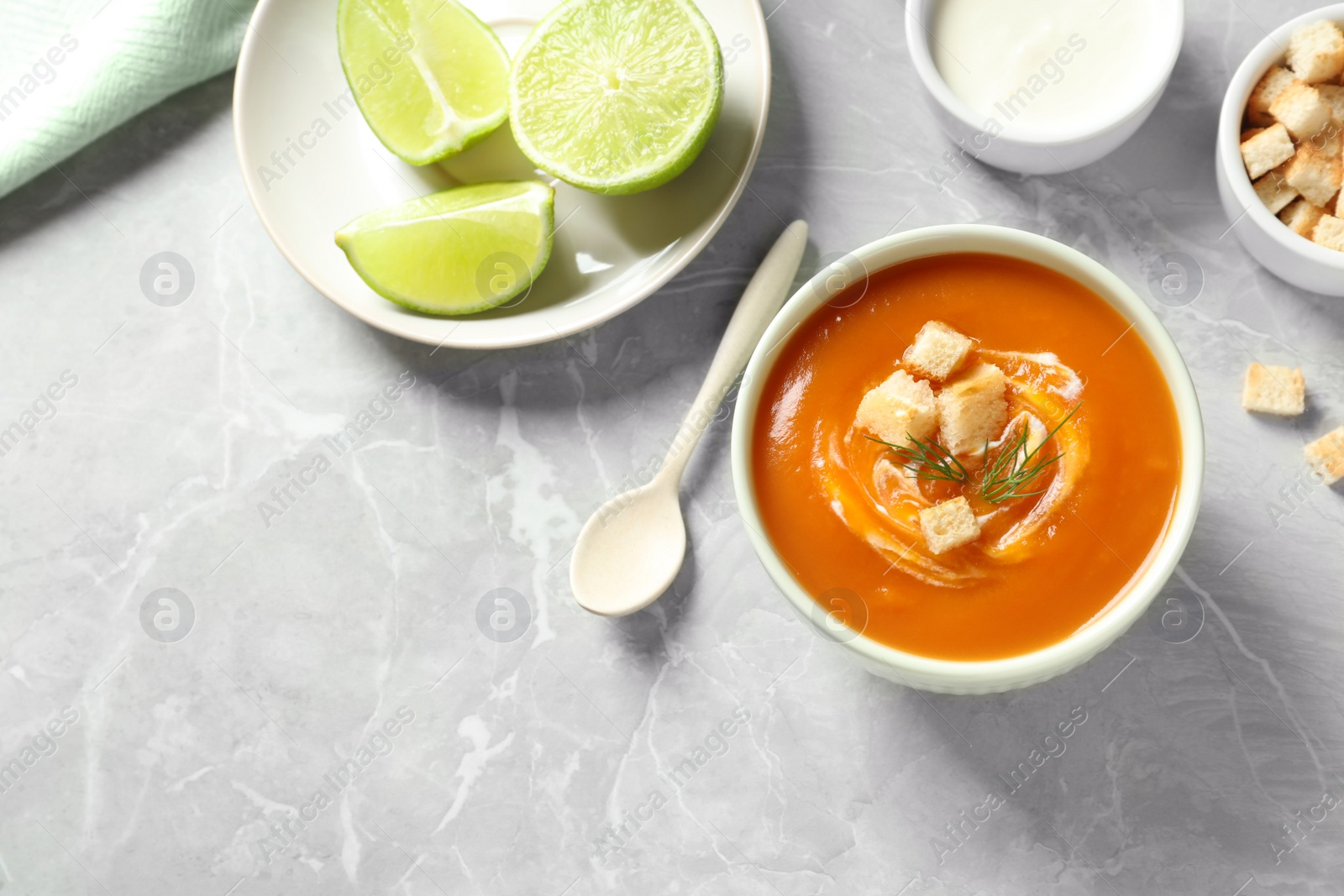 Photo of Flat lay composition with bowl of tasty sweet potato soup and space for text on grey background