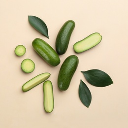 Photo of Whole and cut seedless avocados with green leaves on beige background, flat lay