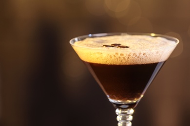 Photo of Glass of delicious Espresso Martini on blurred background. Alcohol cocktail