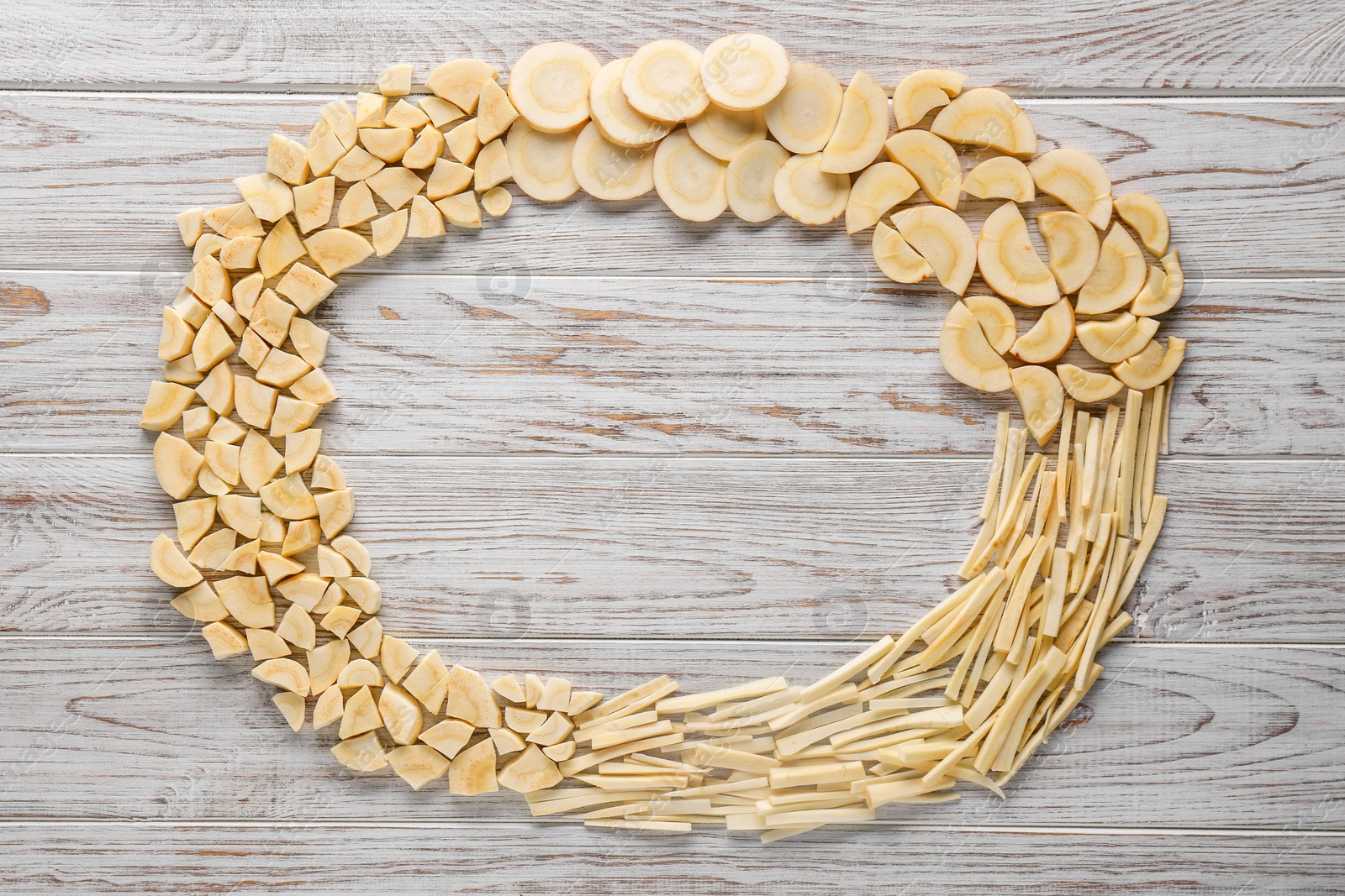 Photo of Frame of cut fresh ripe parsnips on white wooden table, flat lay. Space for text