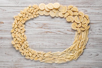 Frame of cut fresh ripe parsnips on white wooden table, flat lay. Space for text