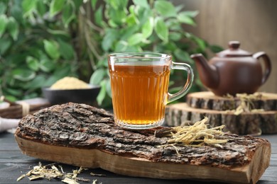Photo of Aromatic licorice tea in cup on black wooden table
