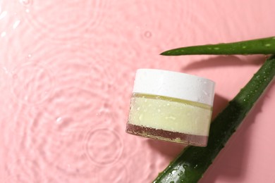 Photo of Jar of cosmetic product and aloe leaves in water on pink background, flat lay. Space for text