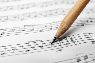 Photo of Sheet with music notes and pencil as background, closeup