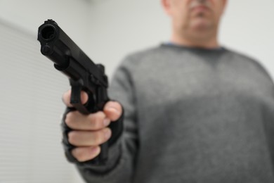 Photo of Dangerous criminal with gun indoors, selective focus. Armed robbery