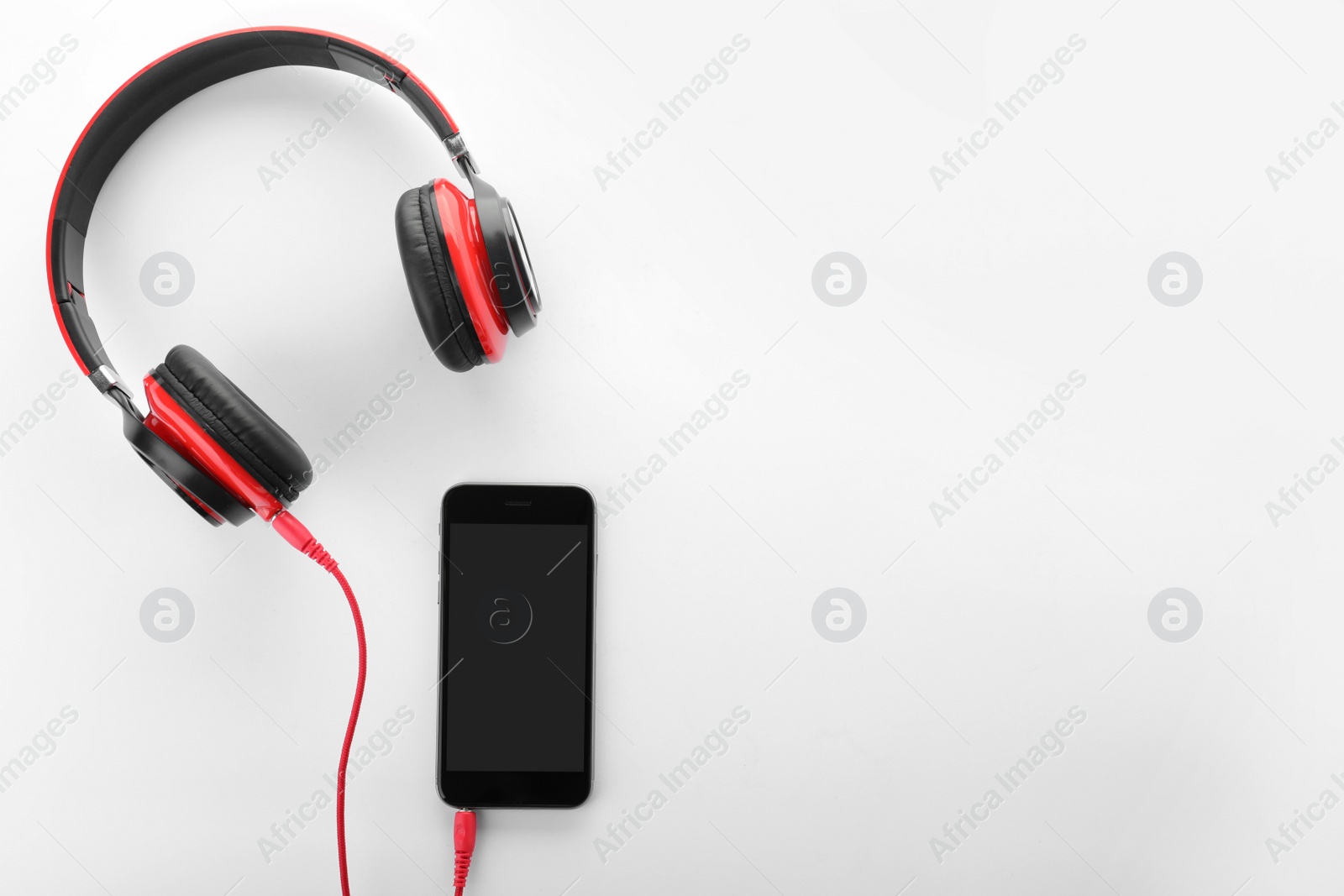 Photo of Smartphone with headphones on white background, top view. Space for text