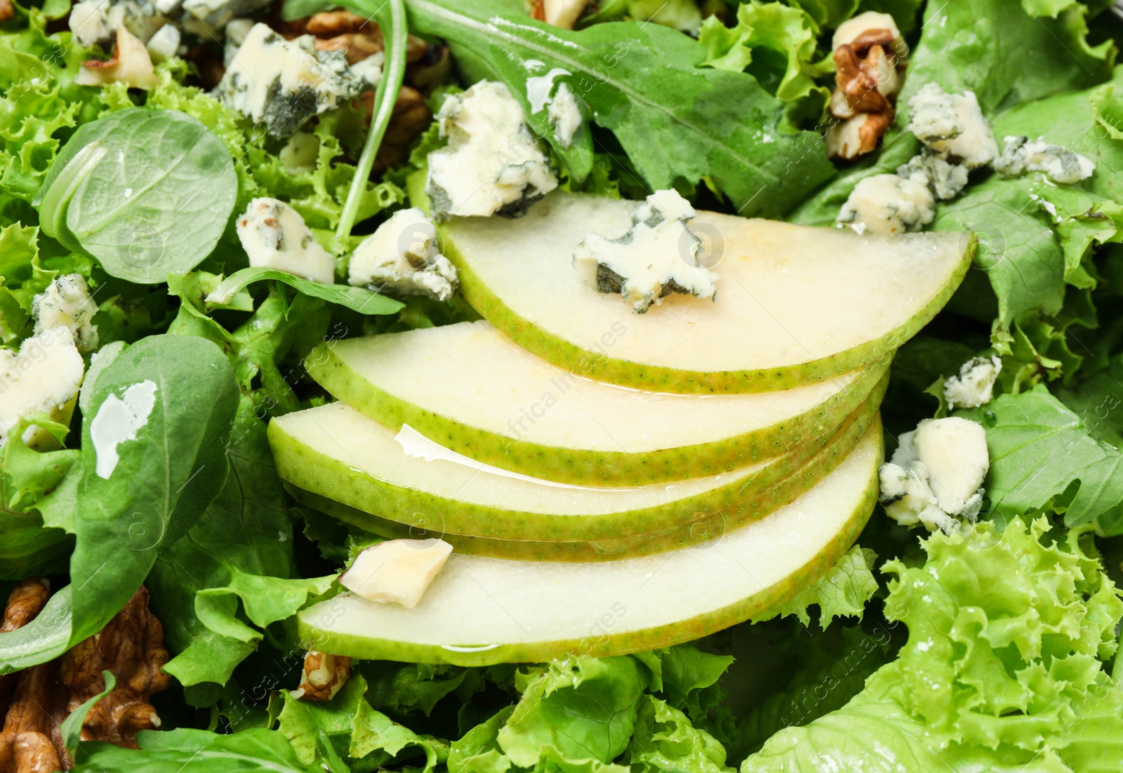 Photo of Delicious fresh salad with pear slices as background, closeup view