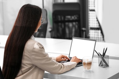 Photo of Woman using modern laptop at white desk in office, back view