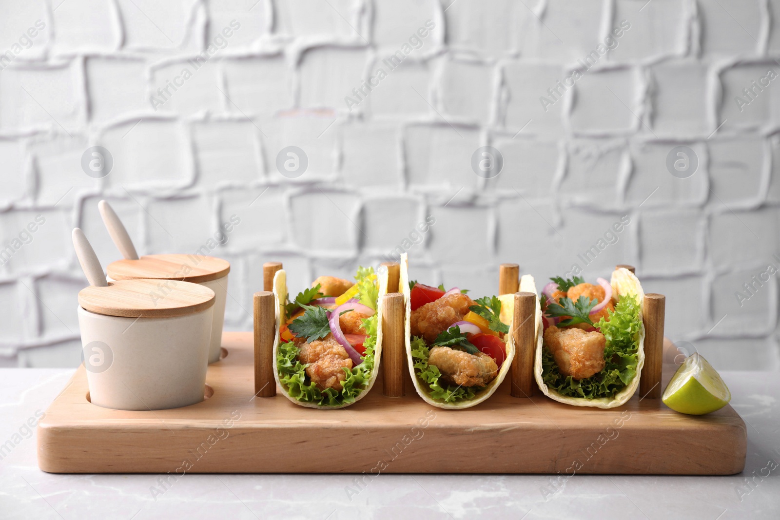 Photo of Yummy fish tacos with sauce on marble table