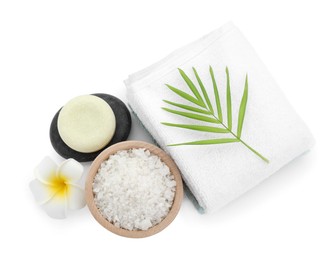 Photo of Bowl of sea salt, towels, massage stones, plumeria flower and palm leaf isolated on white, top view. Spa treatment