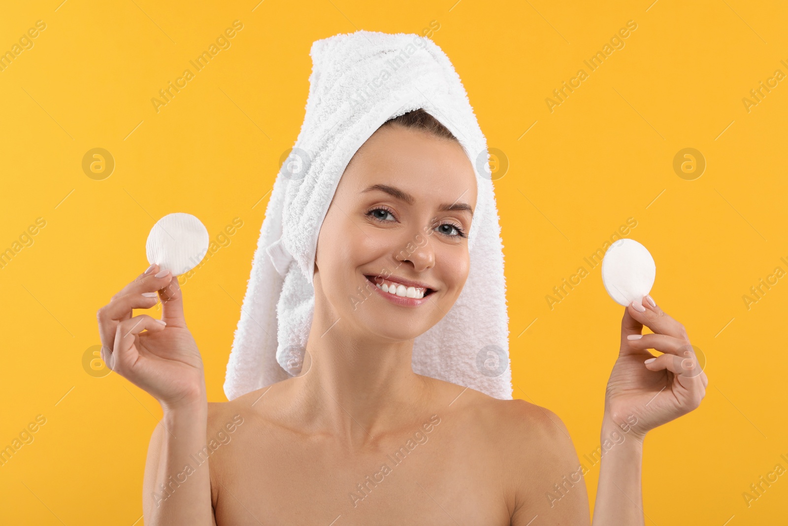 Photo of Removing makeup. Smiling woman with cotton pads on yellow background