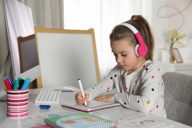 Little girl learning English indoors at online lesson