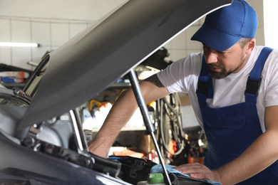 Professional auto mechanic fixing modern car in service center