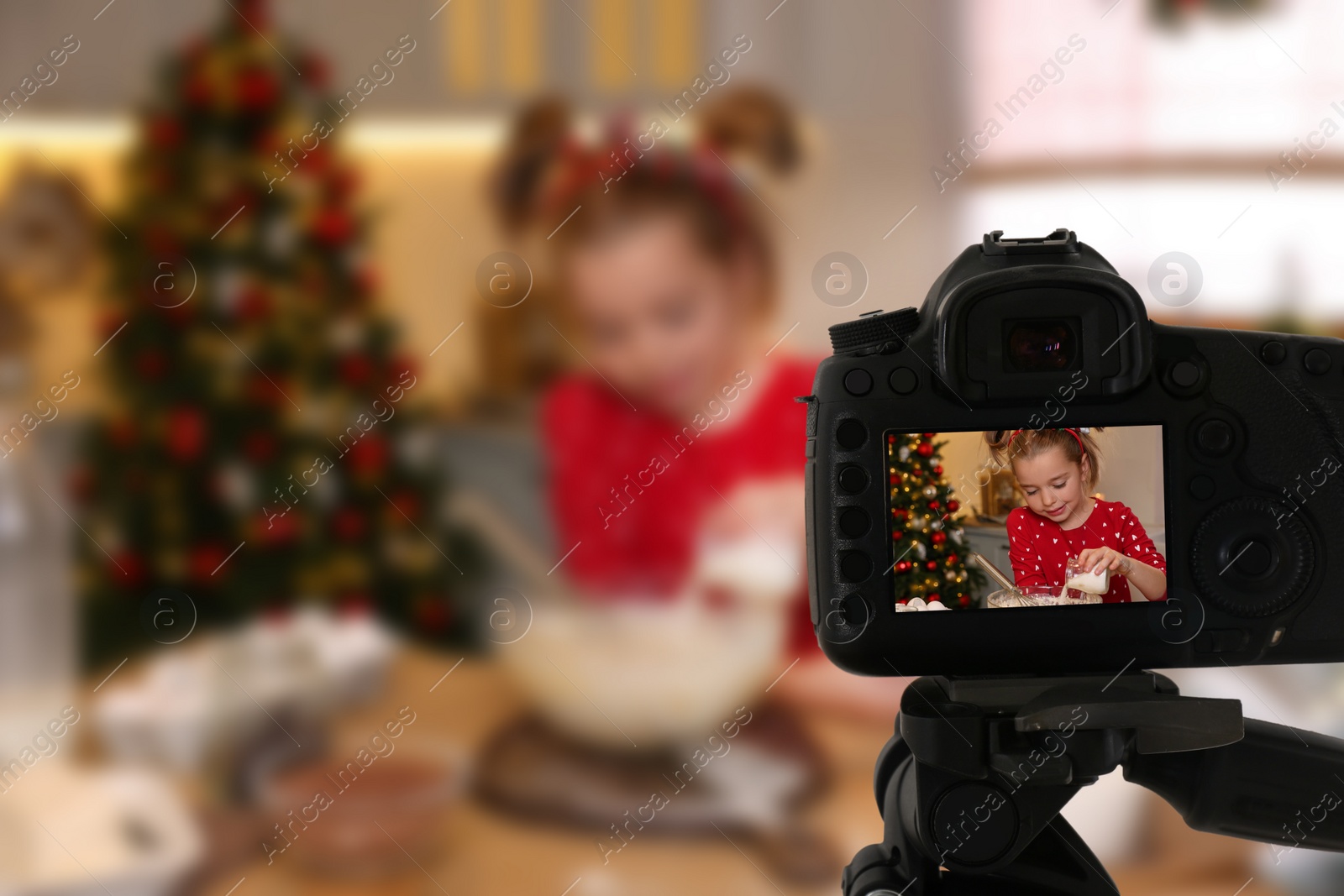 Image of Cute little girl making dough, selective focus on camera display