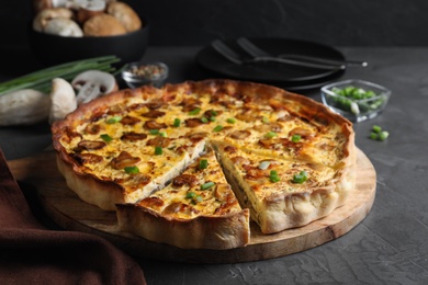 Photo of Delicious pie with mushrooms and cheese served on dark grey table