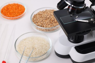 Photo of Food Quality Control. Microscope, petri dishes with different products and other laboratory equipment on white table, closeup