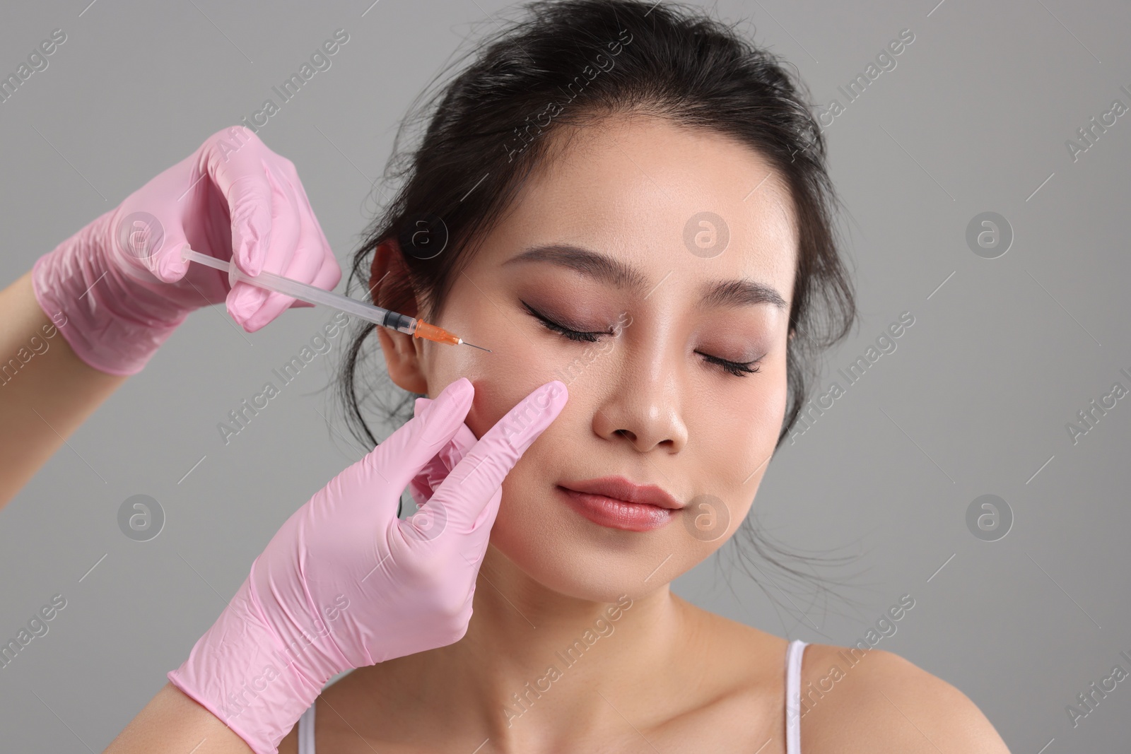 Photo of Woman getting facial injection on grey background