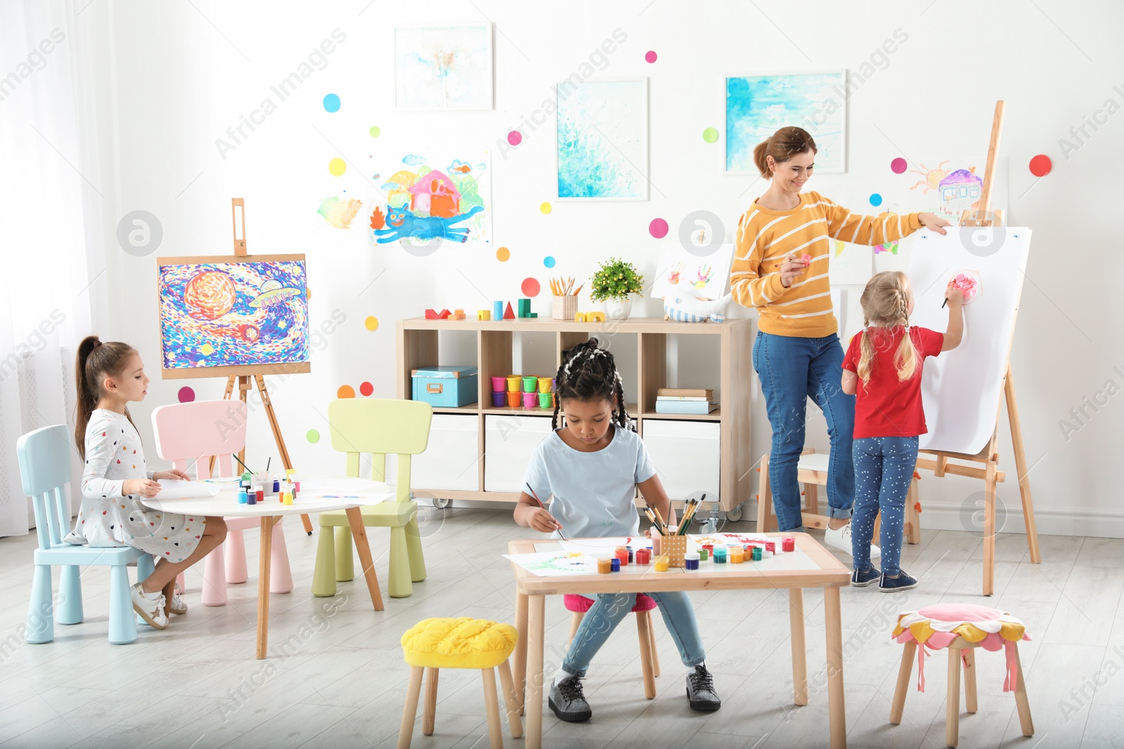 Photo of Children with female teacher at painting lesson indoors