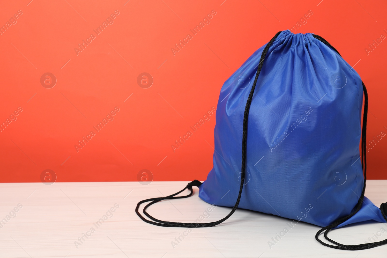 Photo of Blue drawstring bag on white wooden table. Space for text