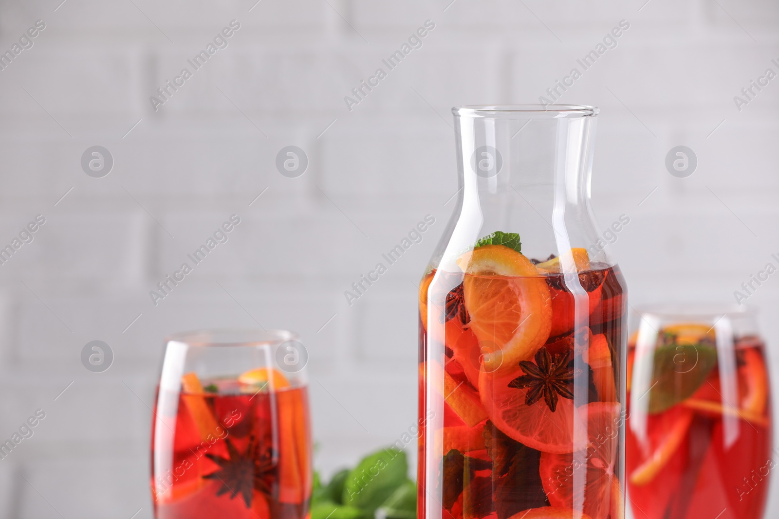 Photo of Delicious punch drink against white brick wall, closeup. Space for text