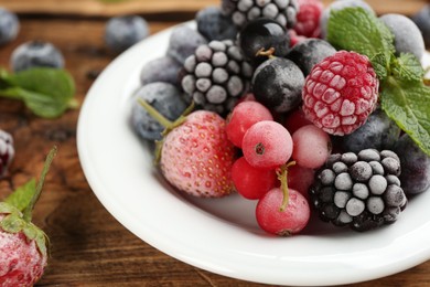 Photo of Mix of different frozen berries on wooden table, closeup