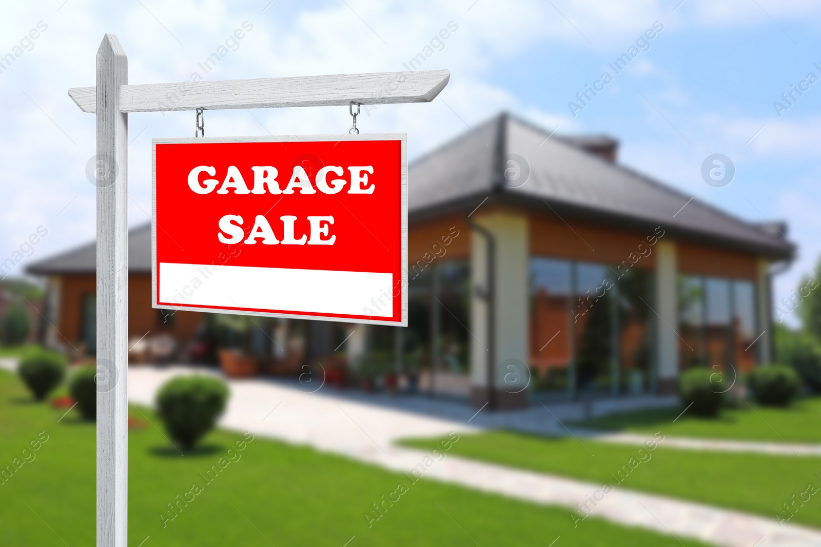 Image of Sign with text GARAGE SALE and blurred view of modern house