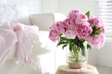 Photo of Bouquet of beautiful peonies on pouf indoors. Space for text