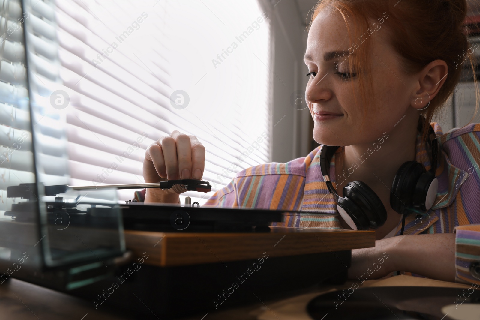 Photo of Young woman using turntable at home, closeup