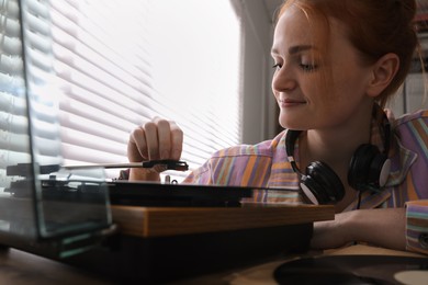 Photo of Young woman using turntable at home, closeup