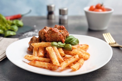 Delicious pasta with meatballs and tomato sauce on table