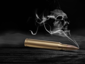 Image of Bullet with skull shaped smoke on black wooden table